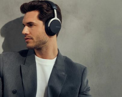 Casque circum-aural noir en plastique, arceau rembourré et liserés argentés, profil gauche, homme en blazer gris