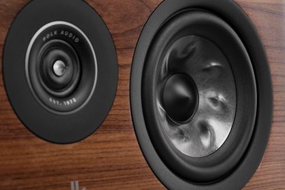 Centrální reproduktor Polk Audio R400 v ořechovém provedení, pohled zepředu a z boku, černý kruhový reproduktor, tmavý dřevěný kryt