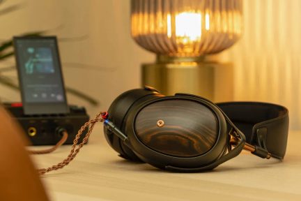 Cuffie audio nere e rame, padiglioni in pelle, archetto imbottito, cavo intrecciato, collegato a un lettore audio portatile nero