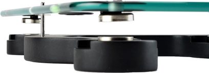 Vibrationsdämpfer Relaxa Tablette 530 Glas, Nahaufnahme von 3 schwarzen zylindrischen Füßen unter einer transluzenten grünen Glasplatte