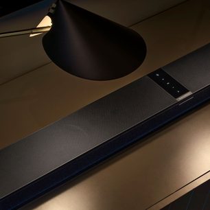 Black Bowers & Wilkins Panorama 3 soundbar under a TV, front view, dark ambient lighting