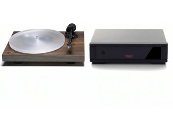 Gira-discos Rega com base castanha, prato translúcido e braço preto, acompanhado de uma caixa preta e cinzenta
