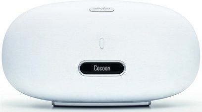 Belaidė prijungiama garso kolonėlė "Denon Stream DS501", baltos spalvos, ovalios formos, su priekinėmis grotelėmis ir centriniu LED ekranu, rodančiu "Cocoon"