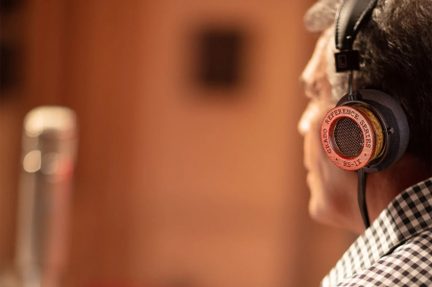 Ακουστικά Grado Reference Series RS-1X στο κεφάλι, προφίλ, καρό πουκάμισο, θολό μικρόφωνο στο φόντο