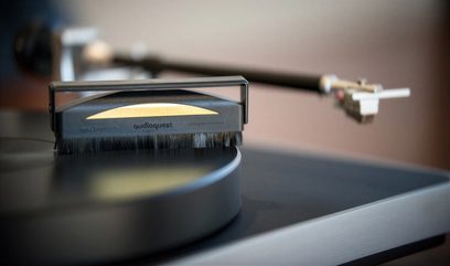 Escova antiestática Audioquest para discos de vinil, cabo preto, cerdas amarelas, colocada em uma bandeja de toca-discos
