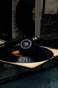 Åben hi-fi hovedtelefon Grado SR125x i sort, vist i trekvartprofil på vinylplader, med æske og jackstik-kabel