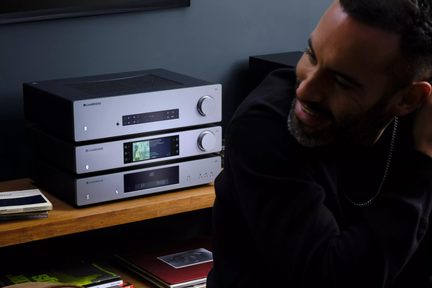 Catena hi-fi Cambridge Audio argento e nero, tre elementi impilati su mobile in legno, uomo in primo piano