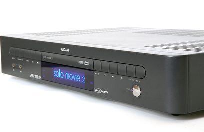 Arcam Solo Movie 5.1 juoda, priekinis vaizdas, mėlynas ekranas rodo "solo movie 2", valdymo mygtukai ir rankenėlė, šlifuoto aliuminio priekinis skydelis