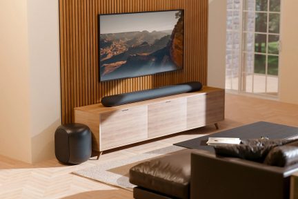 Černý soundbar se subwooferem před nástěnným televizorem v moderním obývacím pokoji