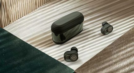 Черни безжични слушалки Devialet с компактен калъф за зареждане върху текстурирана светла повърхност