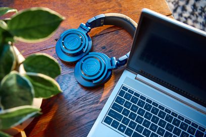 Sluchátka Audio Technica ATH-M50xBT2DS modré položená na stříbrné klávesnici notebooku, pohled shora