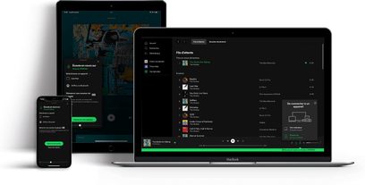 Bærbar computerskærm og tablet, der viser Spotify-appens brugergrænseflade med afspilningslister og albumcovere