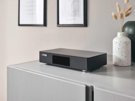 Svart, slankt Canton hi-fi-forsterker med glassfront på moderne TV-benk