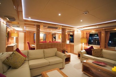 Luksuriøst yachtinteriør med beige sofaer, træbordplader, brune gardiner og indbygningsbelysning i loftet