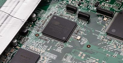 Grønt printplade med sorte og sølvfarvede elektroniske komponenter fra en Denon AVR-X2600H DAB sort hjemmebiografsforstærker, tæt på visning