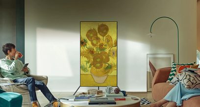 Oliemaleri af gule solsikker i en vase på et lavt bord foran en brun sofa, hvor en lille dreng sidder