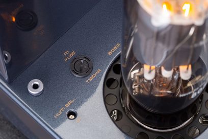 Nærbilde ovenfra av Cayin Jazz 100 svart integrert rørforsterker, mørkt metallchassis med oransje påskrifter, glødende 805A-rør og A1 sikringsholder