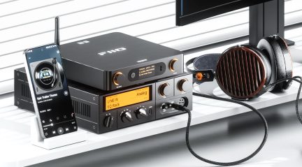 Kompakt sort lydanlæg med smartphone, forstærker med orange skærm og sort-brune kablede around-ear-hovedtelefoner