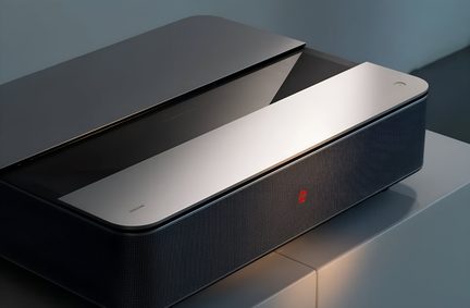 Ultrakortkastende laserprojektor i metalgrå med minimalistisk, firkantet design, placeret på stue-møbel