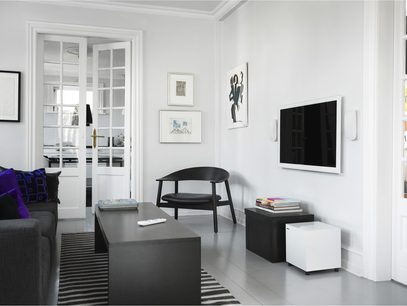 Minimalistisk, moderne hvid stue med grå sofa, sort sofabord, sorte og hvide møbler, abstrakt sort-hvid maleri på væggen