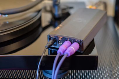 Phono-forforstærker iPhono3 micro Black Label, rektangulært sort kabinet, lilla og sorte RCA-stik, tekstureret overflade, bagfra set