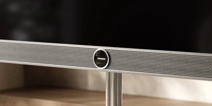 Srebrny soundbar z perforowaną maskownicą i centralnym okrągłym głośnikiem, widok z przodu