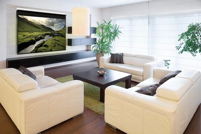 Soggiorno moderno con divani beige, tavolino in legno scuro, piante verdi e grande schermo piatto a parete che mostra un paesaggio montuoso con un fiume