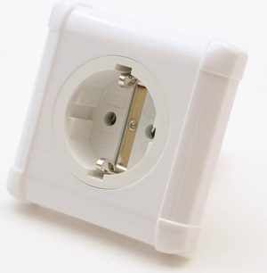 Hvid stikkontakt på væggen med vinkelformet hanstik i forgyldt metal, set tæt på forfra