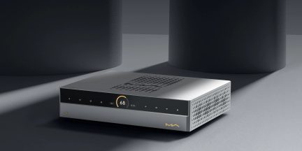Sølvfarvet audiokabinet i børstet aluminium, sort glasfront med cirkulært display “68”, række af berøringsfølsomme knapper, ventilationsgitre på toppen og siden, set fra højre forreste trekvart vinkel