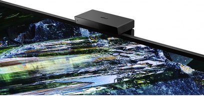 Sony 77A95L-fladskærm set fra en trekvart vinkel forfra, slukket og viser et abstrakt billede med blå og grønne refleksioner