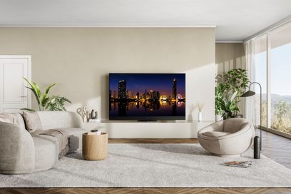 Téléviseur Panasonic TX-65MZ1500E affichant une ville illuminée la nuit, posé sur un meuble dans un salon moderne et lumineux