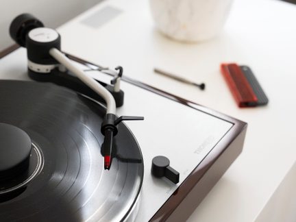 Gramofon s tonskim krožnikom in črnim vinilnim diskom, pogled od zgoraj, kontrolni gumb, valjast predmet in rdeča škatla na desni