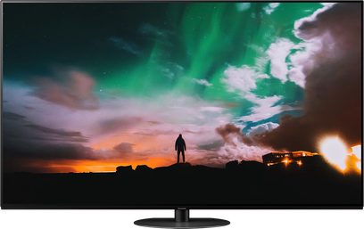 Panasonic TX-65JZ980E-fladskærm, der viser en menneskelig silhuet foran en orange og grøn aftenhimmel med skyer