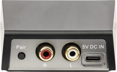 MartinLogan WSK1E trådløs sender i sort børstet metal, close-up af bagsiden med sort Pair-knap, to guldbelagte RCA-stik i rød og hvid mærket R og L, samt USB-C 5 V strømport