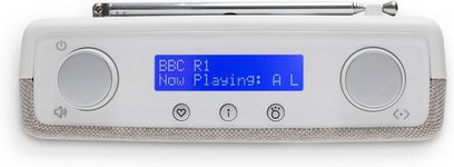Radio de mesa Roberts Play 11 en blanco crema, con acabado en plástico liso y tejido jaspeado. Vista frontal con pantalla LCD azul central, dos grandes botones giratorios plateados a cada lado, fila de pequeños botones con iconos debajo y antena telescópica plegada en la parte superior.