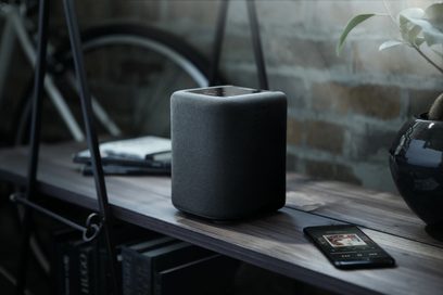 Trådløs, tilsluttet Yamaha WX-010 højttaler i sort, set forfra, placeret på et træbord med en smartphone ved siden af
