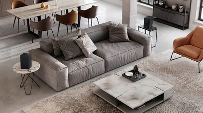 Moderne stue med grå hjørnesofa, orange lænestol, marmor- og metalcoffeborde, beige tæppe med geometriske mønstre