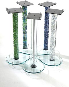 Fire Atacama Audio Aurora 6 højtalere med transparent glaskabinet og farvede grønne og blå fyldningsrør, på rund metalbase
