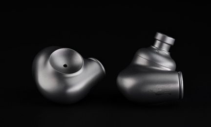 Graue metallische In-Ear-Kopfhörer, matte ergonomische Gehäuse auf schwarzem Hintergrund liegend