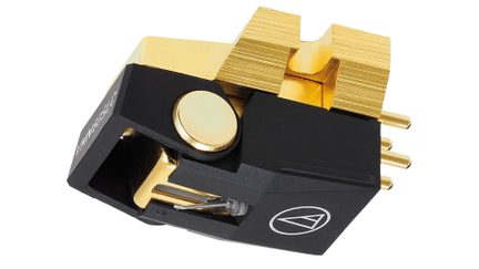 Nærbillede af en sort og gylden phono-celle med et hvidt logo, gyldne stik og en synlig nål