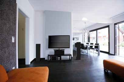 Sort TV-møbel med hylder, i en moderne stue med orange sofa, store vinduer og mørkt trægulv