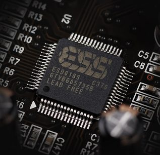 Tæt på et rektangulært sort elektronisk chip med indgraveret "E8001AS GTV8603-44EG LEAD FREE" på et printplade