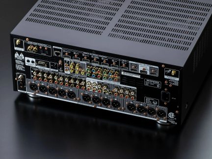 Arrière d'un boîtier AV noir en métal, vue trois-quarts, connecteurs HDMI, RCA et XLR en rangées, grilles de ventilation