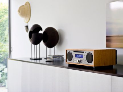 Brunt træ hi-fi-anlæg, sølvfarvet front, to runde højttalere, blå skærm, central knap, trekvarts forfra
