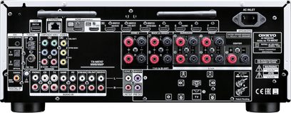 Forsiden af en sølvfarvet Onkyo TX-NR747 hjemmebiografsforstærker med talrige stik, knapper og displayskærm