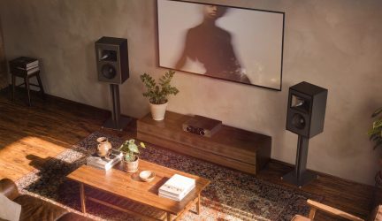 Coppia di diffusori da scaffale neri su supporti in un soggiorno con mobile TV in legno e amplificatore hi-fi
