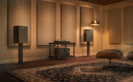 Coppia di diffusori hi-fi neri su supporti, giradischi e amplificatore in salotto acustico