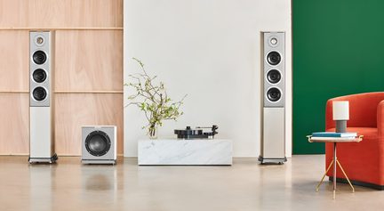 Pohled zepředu na audio soupravu sestávající ze dvou sloupových reproduktorů ve stříbrném kartáčovaném kovovém provedení, každý se čtyřmi kruhovými reproduktory, doplněnou o laděný krychlový subwoofer.