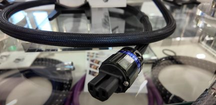 Sort strømkabel med flettet nylonkappe, IEC hunstik i sort plast med blå metalring, close-up i trekvartsvinkel