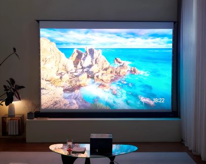 Schermo di proiezione home cinema motorizzato con immagine di mare turchese e scogliere in un soggiorno moderno